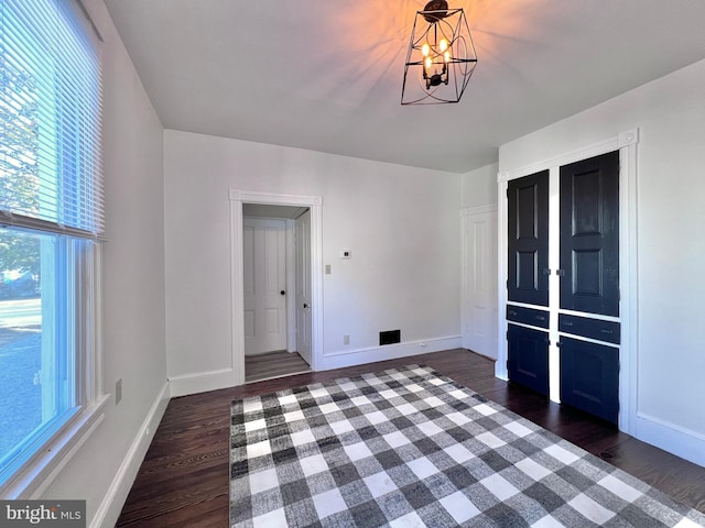 interior space with a healthy amount of sunlight, a chandelier, and dark wood-style flooring