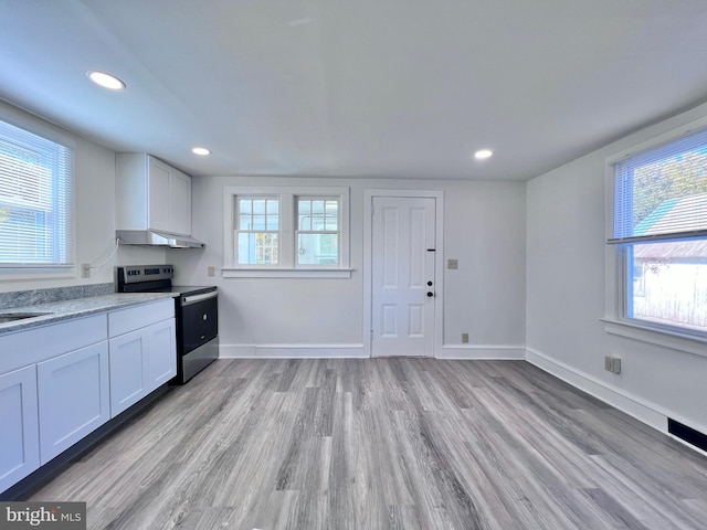 kitchen with stainless steel electric stove, light wood-style floors, white cabinets, light stone countertops, and recessed lighting
