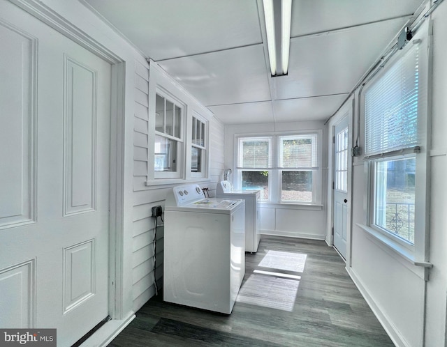 washroom featuring a wealth of natural light, dark wood-type flooring, washer and clothes dryer, and laundry area