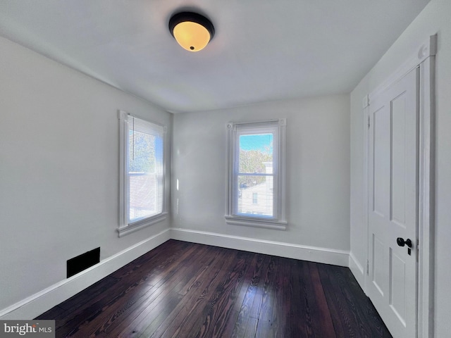 empty room with baseboards and dark wood-style flooring