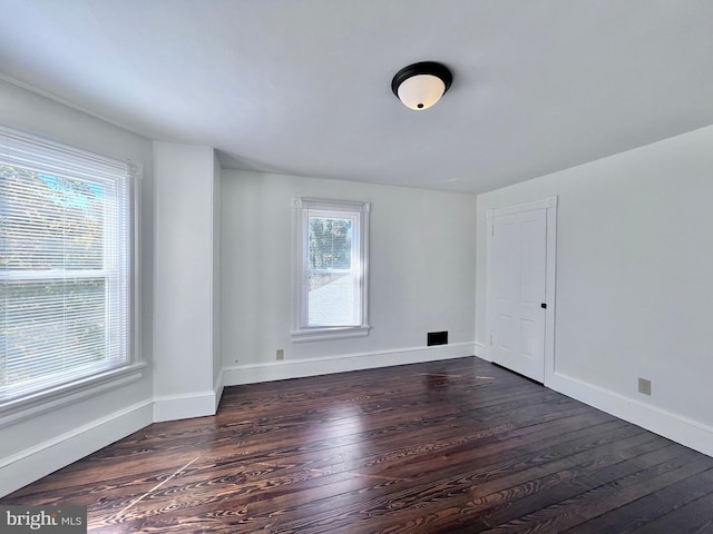 spare room featuring dark wood finished floors and baseboards