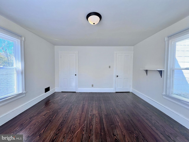 unfurnished room featuring baseboards and dark wood-style floors