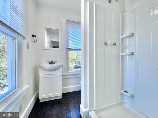 bathroom featuring a healthy amount of sunlight, vanity, wood finished floors, and a shower