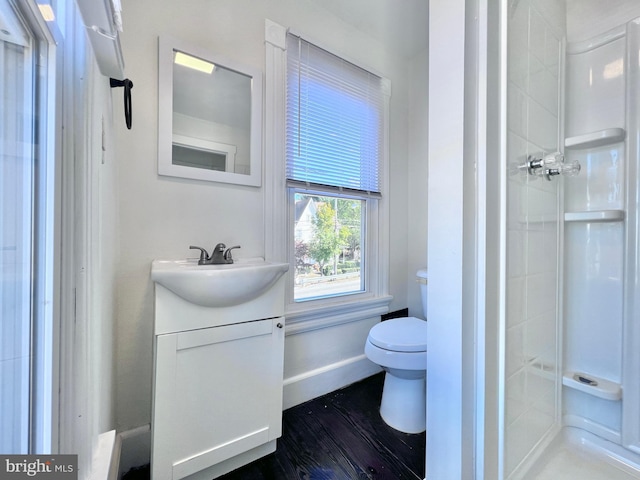full bath featuring toilet, wood finished floors, a stall shower, vanity, and baseboards