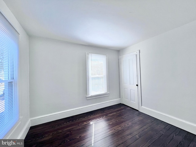 empty room featuring baseboards and dark wood-style floors
