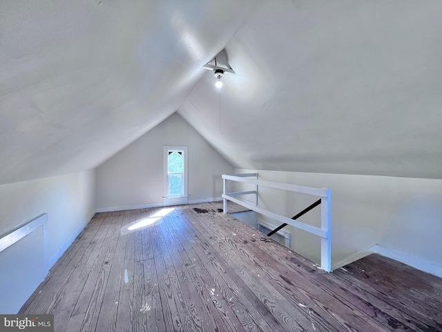 additional living space with wood-type flooring, vaulted ceiling, and baseboards