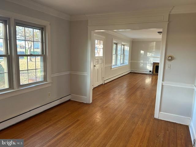 empty room with a baseboard heating unit, wood-type flooring, and ornamental molding