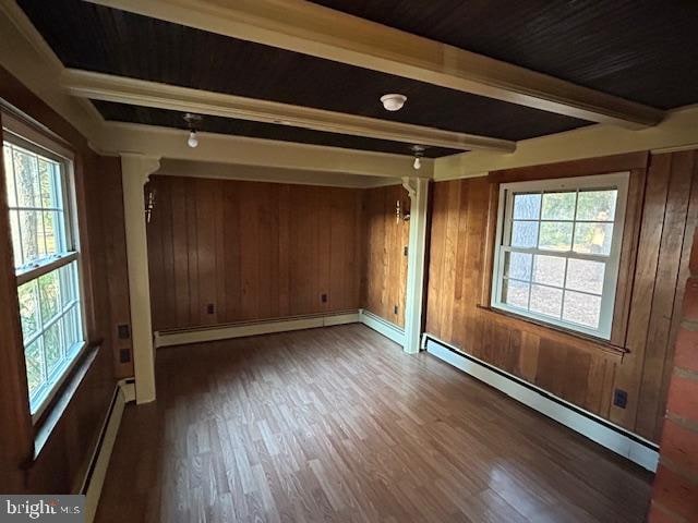 unfurnished room with beamed ceiling, wooden walls, dark hardwood / wood-style floors, and a baseboard heating unit