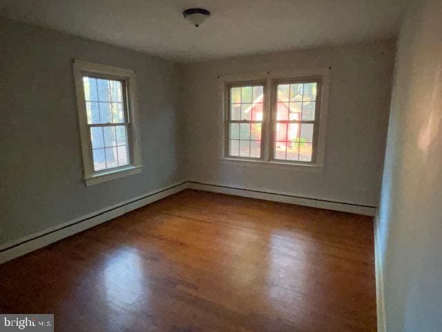 spare room with hardwood / wood-style flooring, a healthy amount of sunlight, and a baseboard radiator