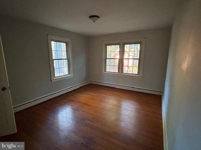 unfurnished room featuring baseboard heating and dark hardwood / wood-style floors