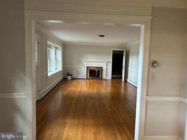 unfurnished living room with hardwood / wood-style floors, crown molding, and a baseboard heating unit