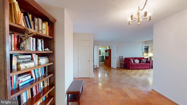 hall featuring a textured ceiling, a notable chandelier, and light parquet flooring