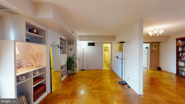 corridor with light hardwood / wood-style floors and a chandelier