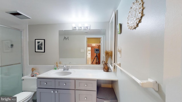 bathroom with walk in shower, vanity, and toilet