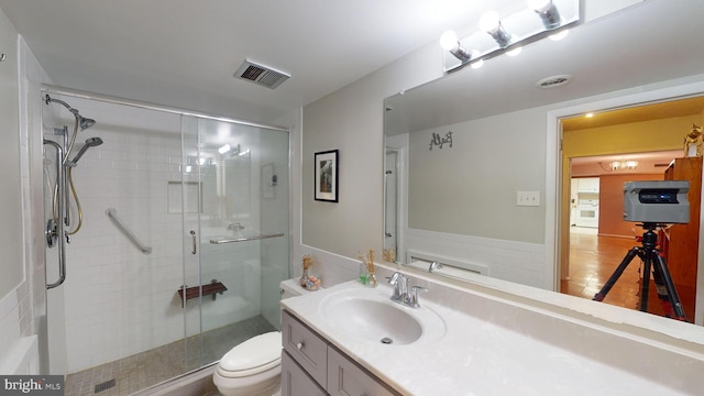 bathroom with a shower with door, vanity, and toilet