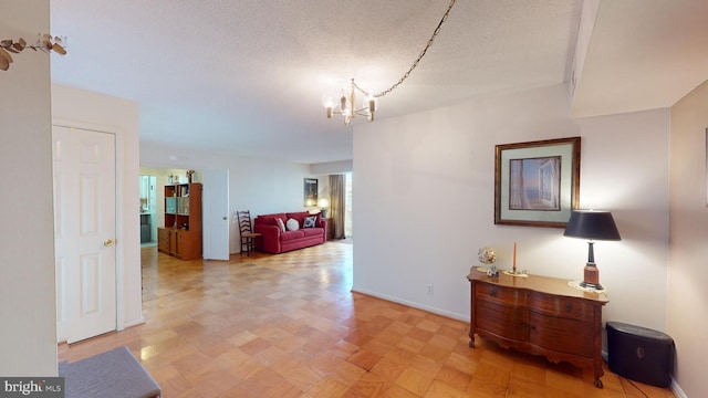 hallway featuring a textured ceiling and an inviting chandelier