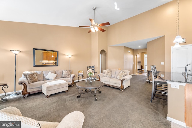 carpeted living room featuring a high ceiling and ceiling fan