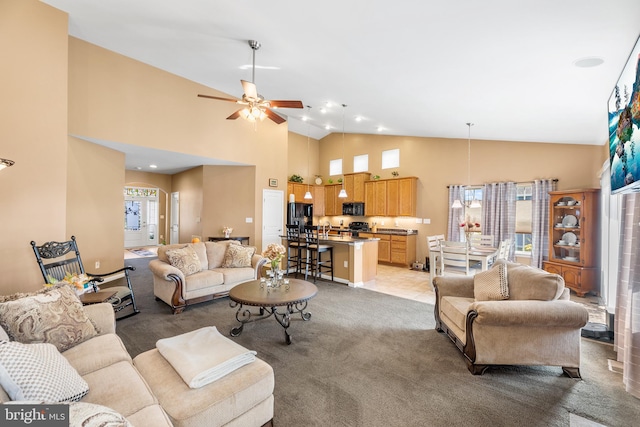 carpeted living room with ceiling fan and high vaulted ceiling