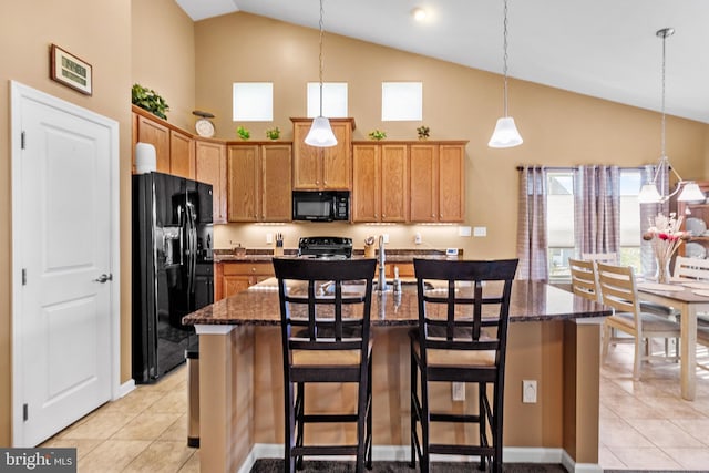 kitchen featuring a kitchen breakfast bar, black appliances, dark stone counters, and light tile patterned floors