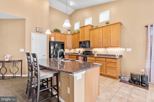 kitchen with a center island with sink, sink, black appliances, light tile patterned floors, and high vaulted ceiling