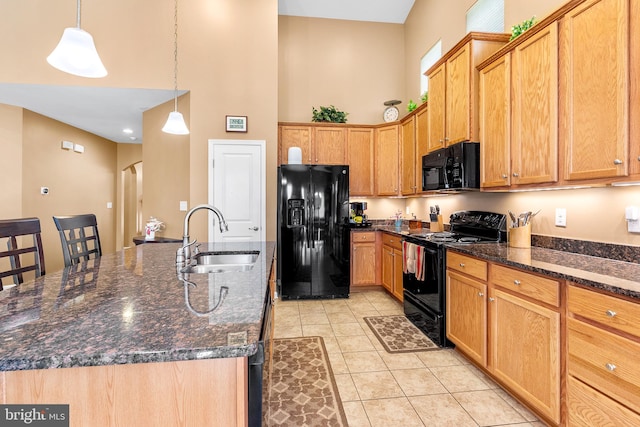 kitchen with an island with sink, sink, black appliances, light tile patterned flooring, and decorative light fixtures