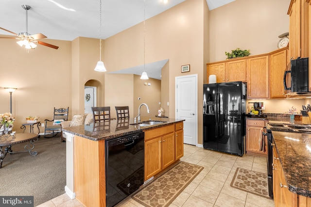 kitchen featuring a center island with sink, sink, black appliances, light tile patterned floors, and high vaulted ceiling