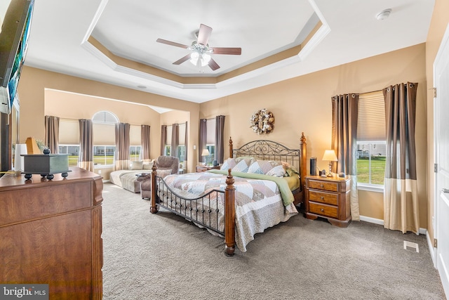 carpeted bedroom with a tray ceiling and ceiling fan