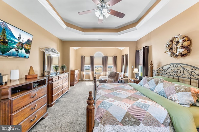 carpeted bedroom featuring ceiling fan, a raised ceiling, and ornamental molding