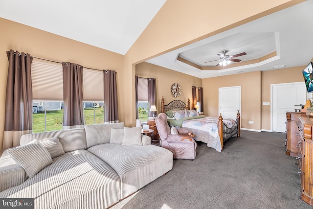 carpeted bedroom with ceiling fan and a raised ceiling