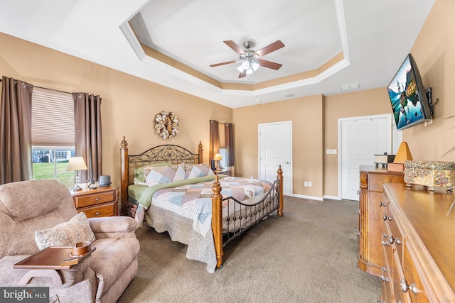 carpeted bedroom featuring a raised ceiling and ceiling fan