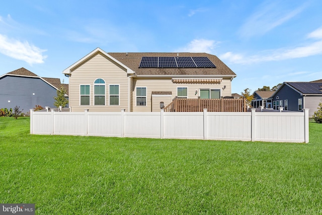 back of property featuring a lawn and solar panels