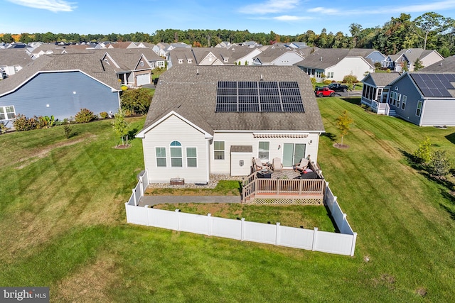 back of property featuring a yard, solar panels, and a wooden deck