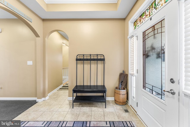 foyer entrance with a tray ceiling and light tile patterned floors