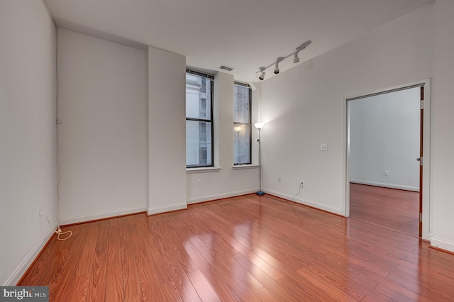 empty room with light hardwood / wood-style flooring and rail lighting