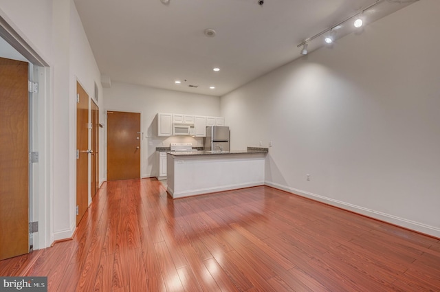 kitchen featuring kitchen peninsula, white appliances, light hardwood / wood-style flooring, stone counters, and white cabinets