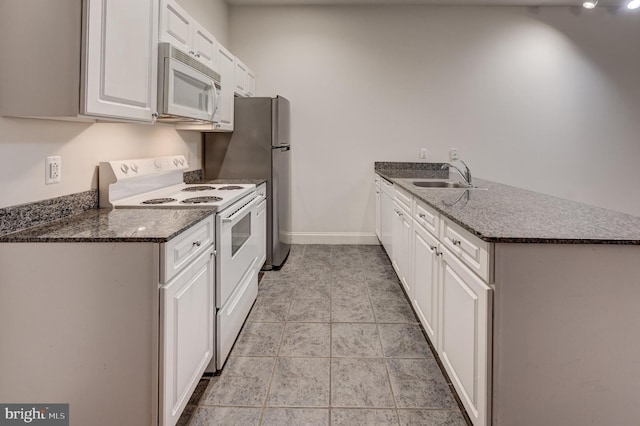 kitchen with white appliances, dark stone counters, sink, white cabinetry, and kitchen peninsula