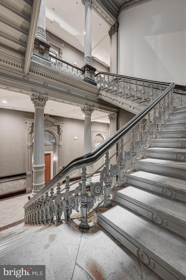 stairs with a towering ceiling and ornate columns