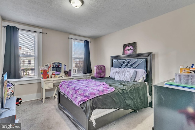 bedroom with a textured ceiling, light colored carpet, and multiple windows