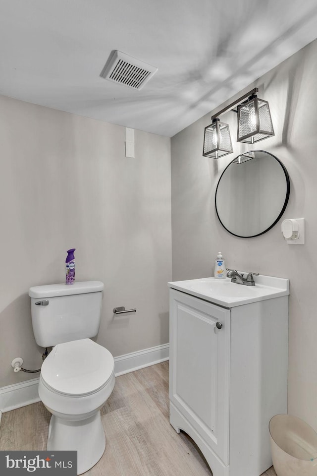 bathroom with hardwood / wood-style flooring, vanity, and toilet