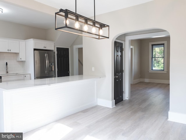 kitchen featuring sink, decorative light fixtures, light hardwood / wood-style flooring, white cabinets, and stainless steel fridge with ice dispenser