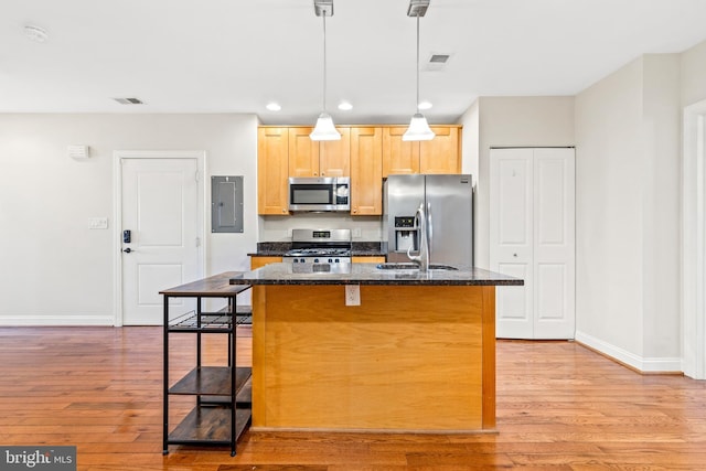 kitchen featuring light brown cabinetry, an island with sink, light hardwood / wood-style floors, stainless steel appliances, and a breakfast bar area