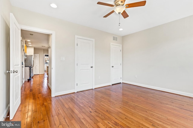 unfurnished bedroom featuring stainless steel refrigerator, hardwood / wood-style flooring, and ceiling fan