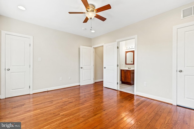 unfurnished bedroom with connected bathroom, ceiling fan, and light hardwood / wood-style flooring