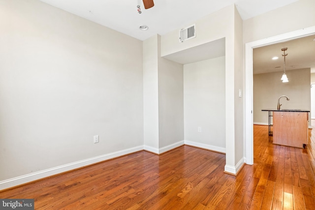 empty room with ceiling fan, wood-type flooring, and sink