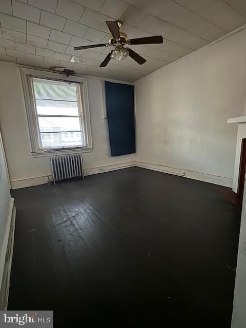 unfurnished room with radiator, ceiling fan, and wood-type flooring