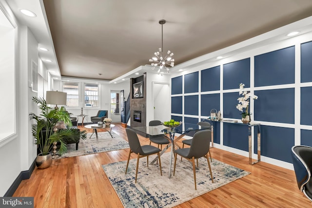 dining area featuring a notable chandelier, hardwood / wood-style floors, and a tile fireplace