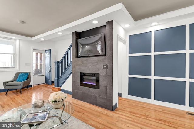 living room featuring a tiled fireplace and hardwood / wood-style floors