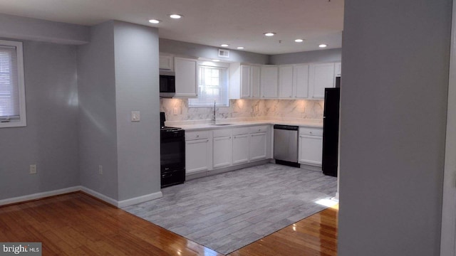 kitchen with black appliances, light wood-type flooring, white cabinets, and sink