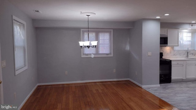 unfurnished dining area with light wood-type flooring, a chandelier, and sink