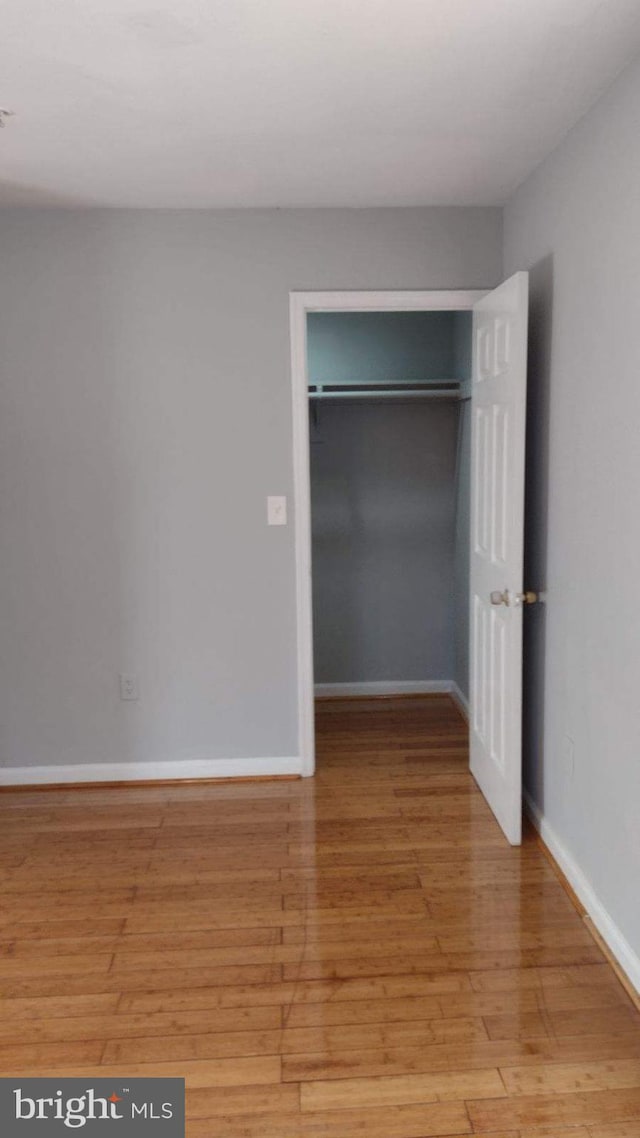 unfurnished bedroom with light wood-type flooring and a closet